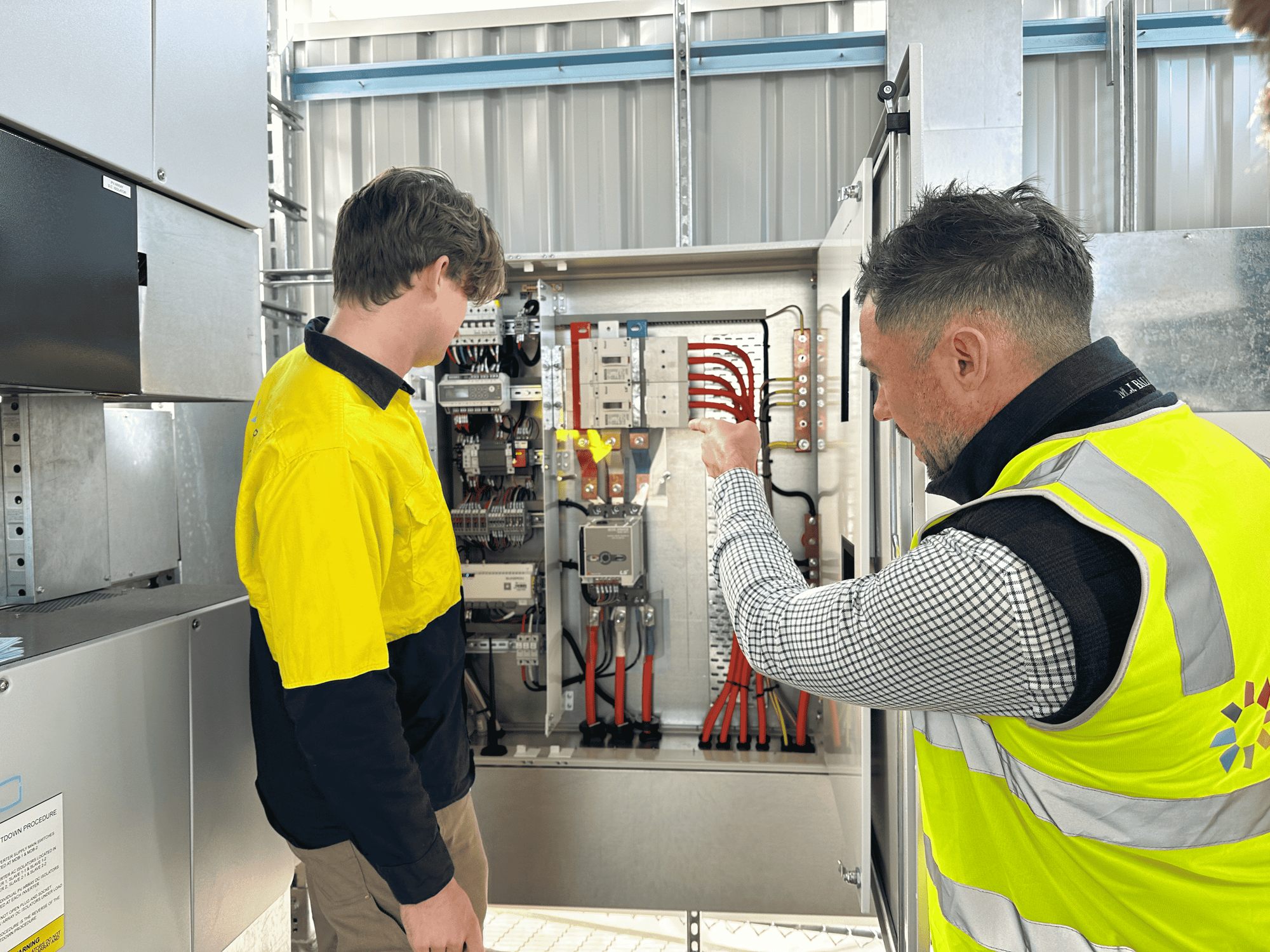 Two safety vest experts performing solar inverter maintenance and repair