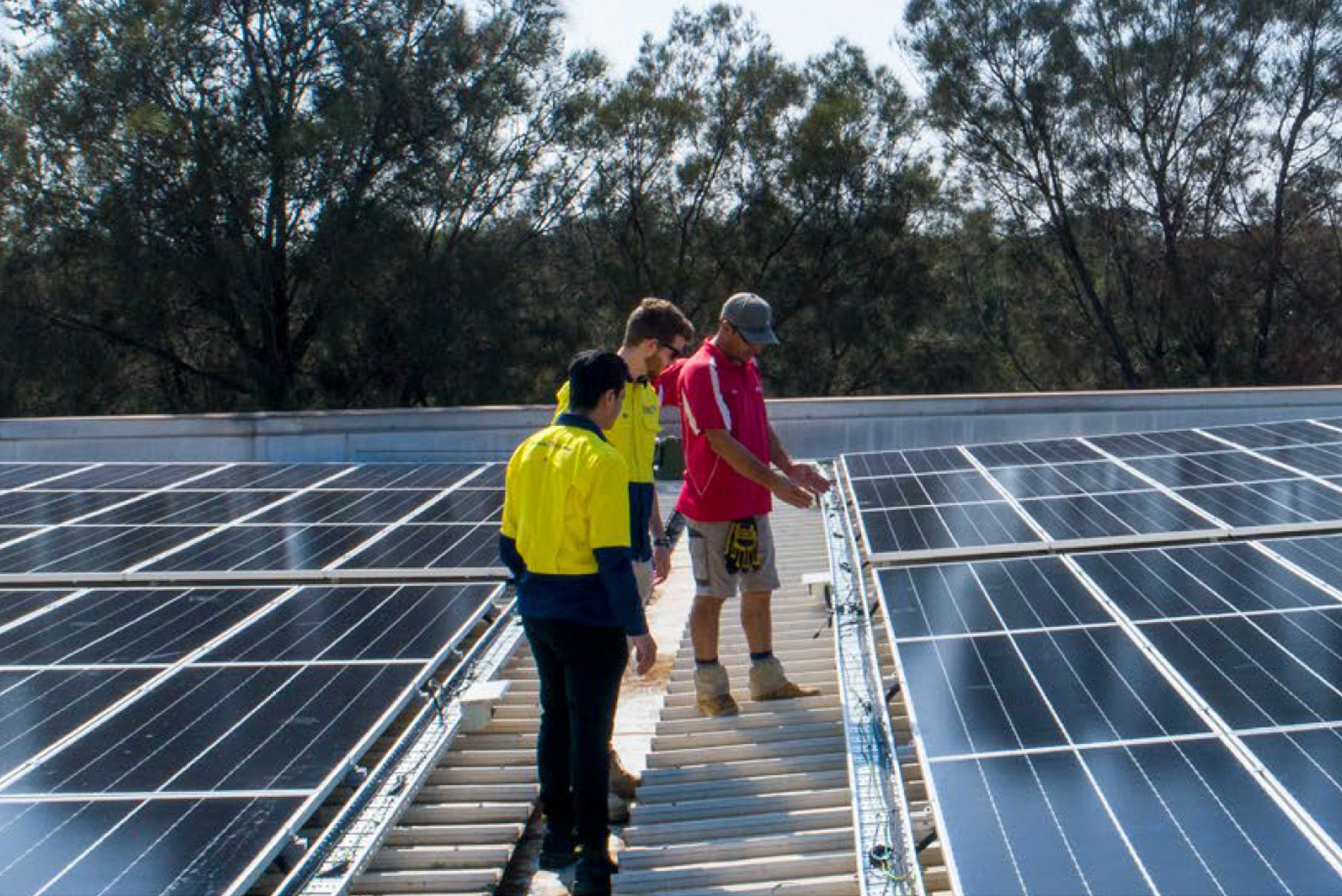 Three solar energy experts inspecting solar panels on a rooftop
